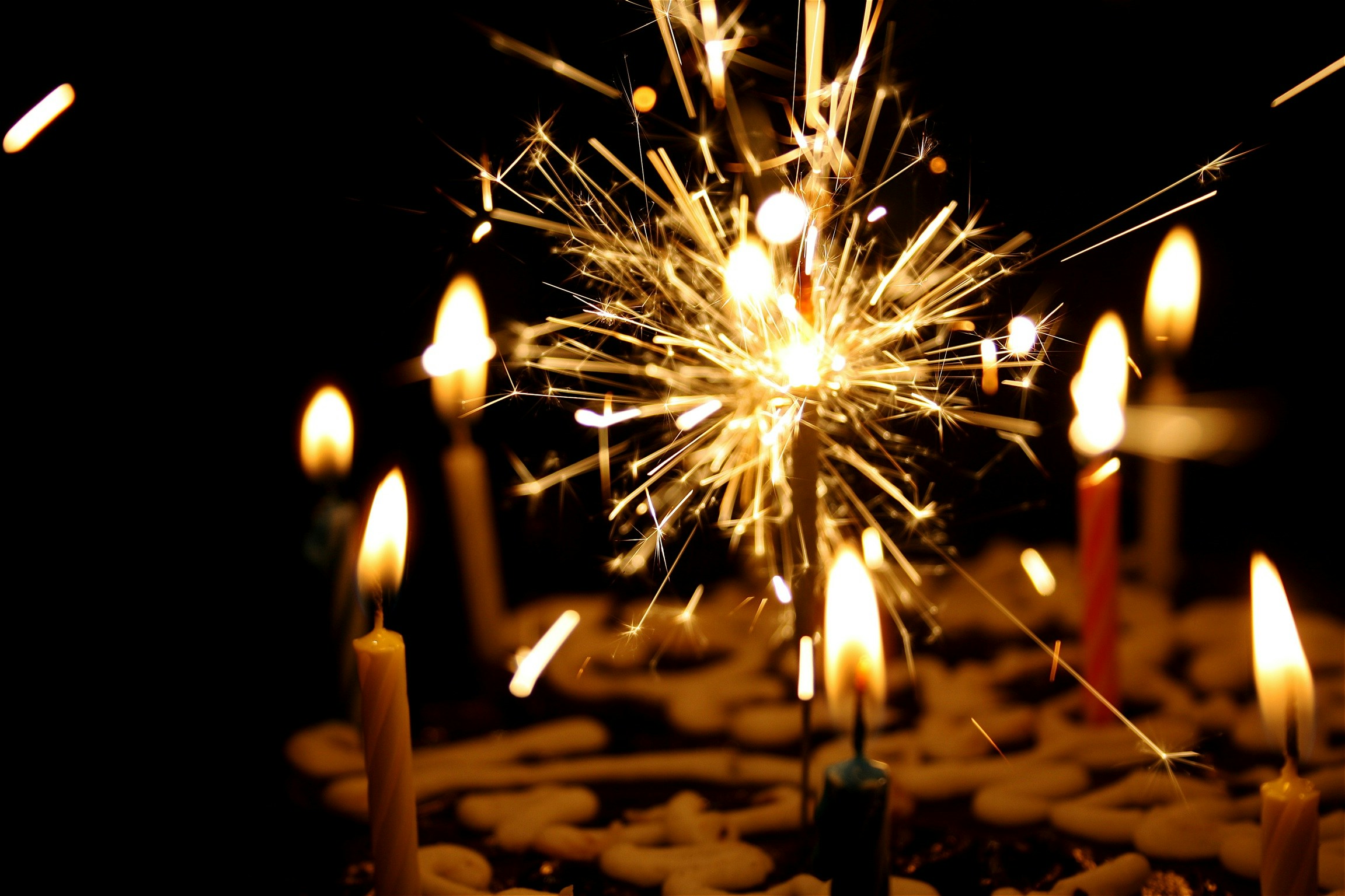 a sparkly candle amid other candles on a birthday cake