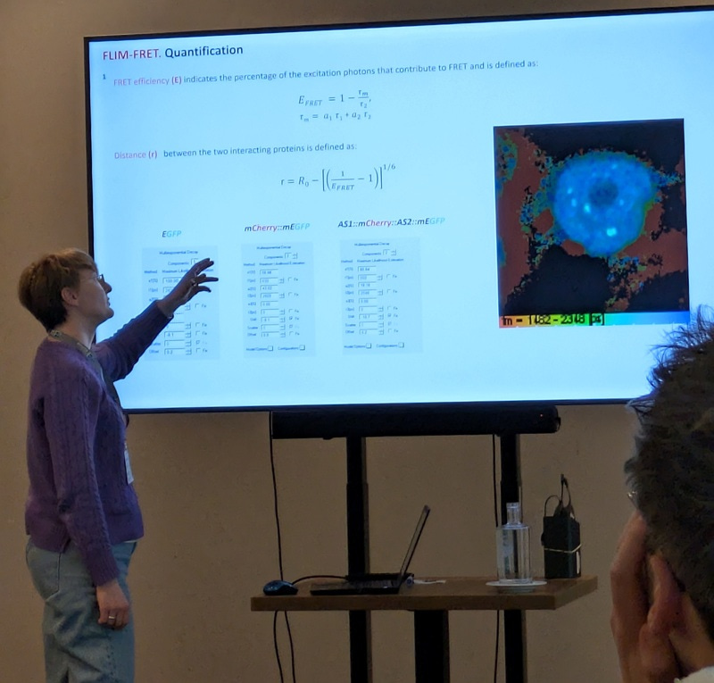 Tatsiana Straub standing by a monitor screen, pointing at the screen.