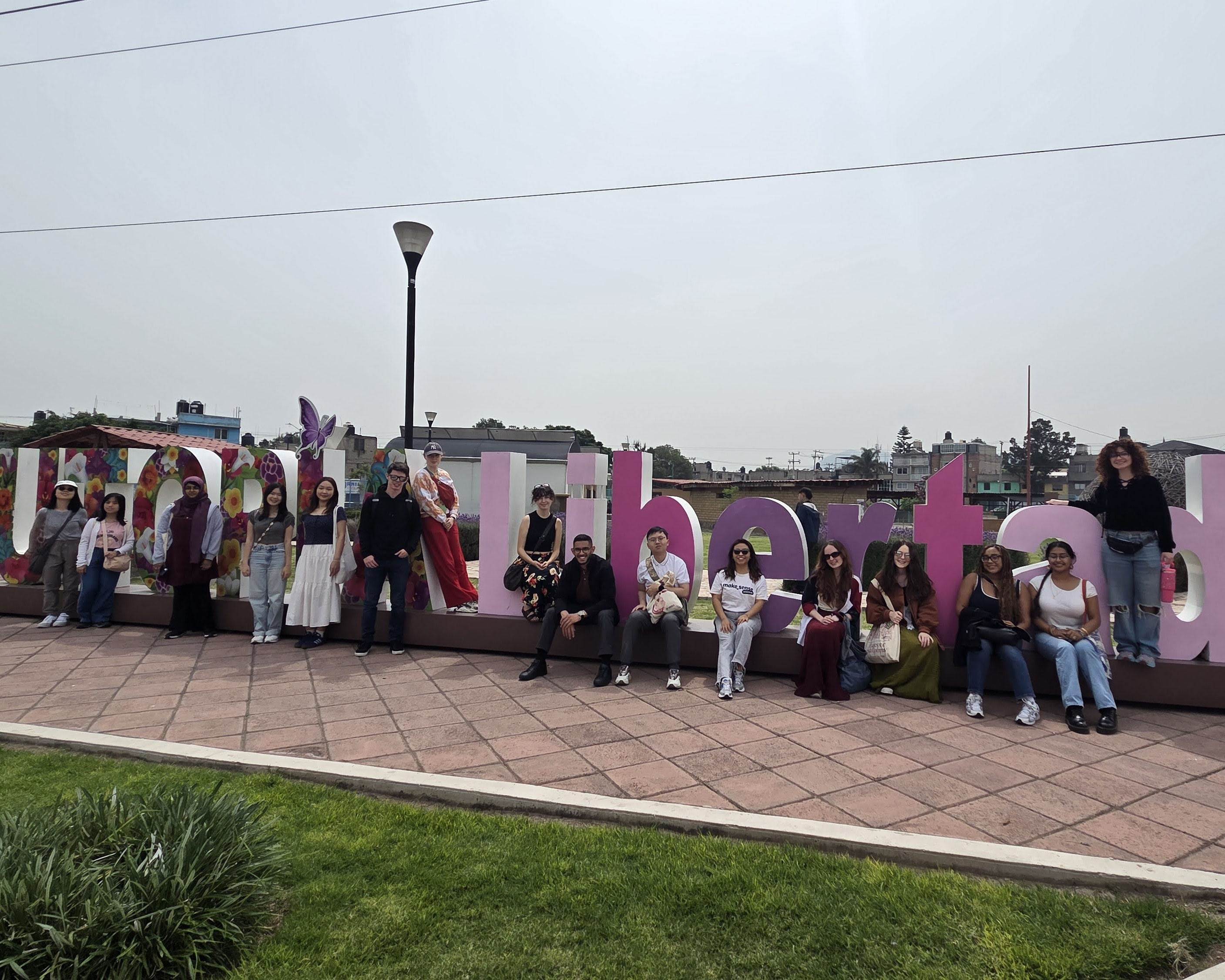 People sitting on big letters that spell out Utopia Libertad.