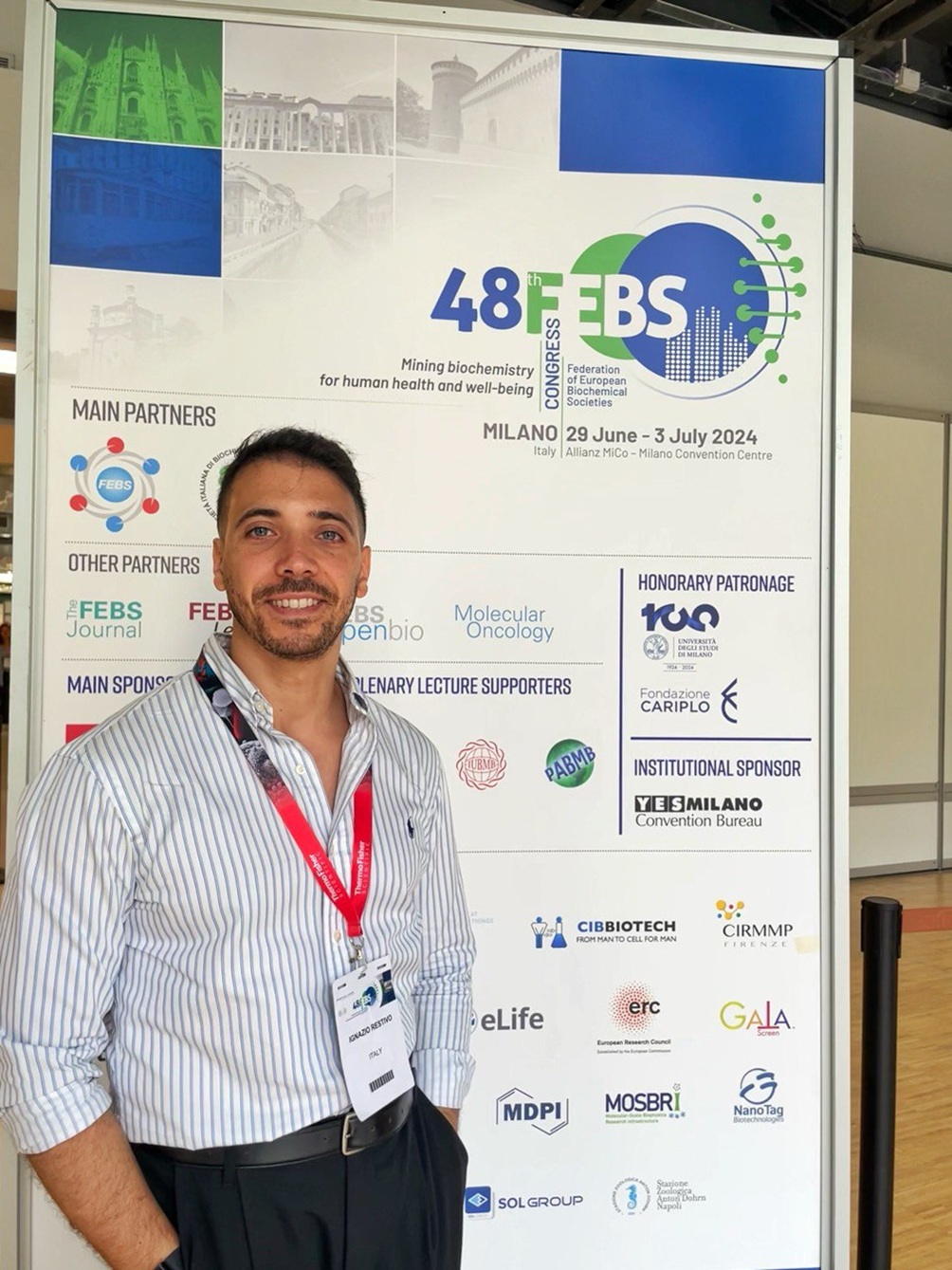 Photo of Ignazio Restivo smiling and standing next to his research poster.