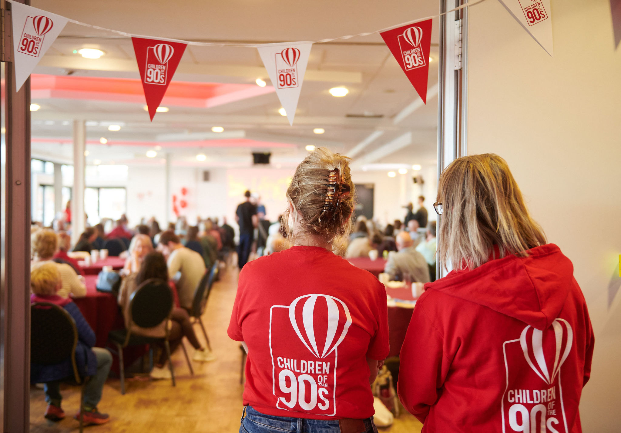 Two women with Children of the 90s t shirts watch celebrations at the 2023 Discovery Day