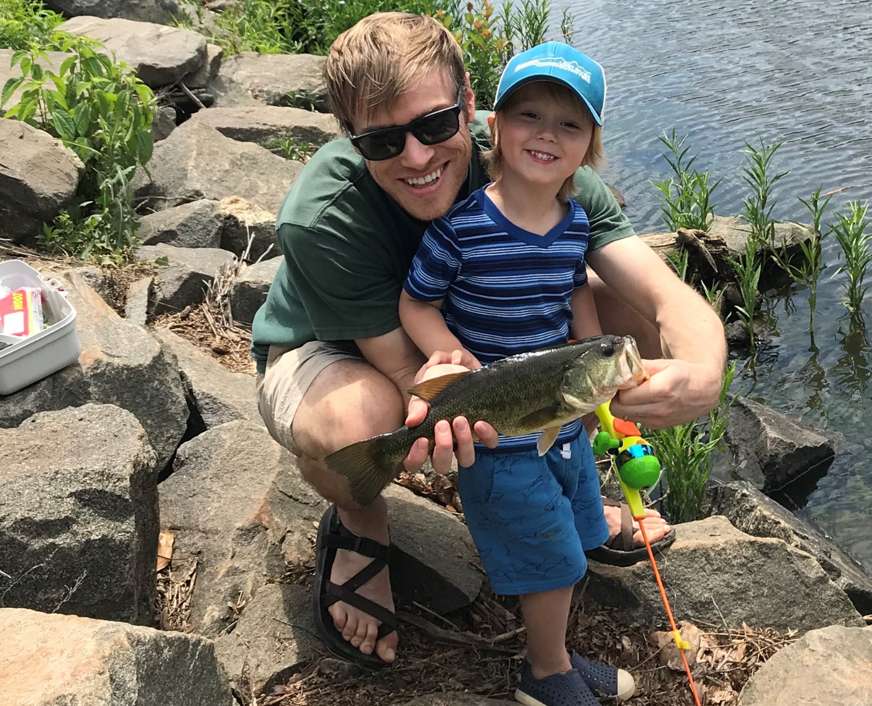 A man and son smiling and holding a fish