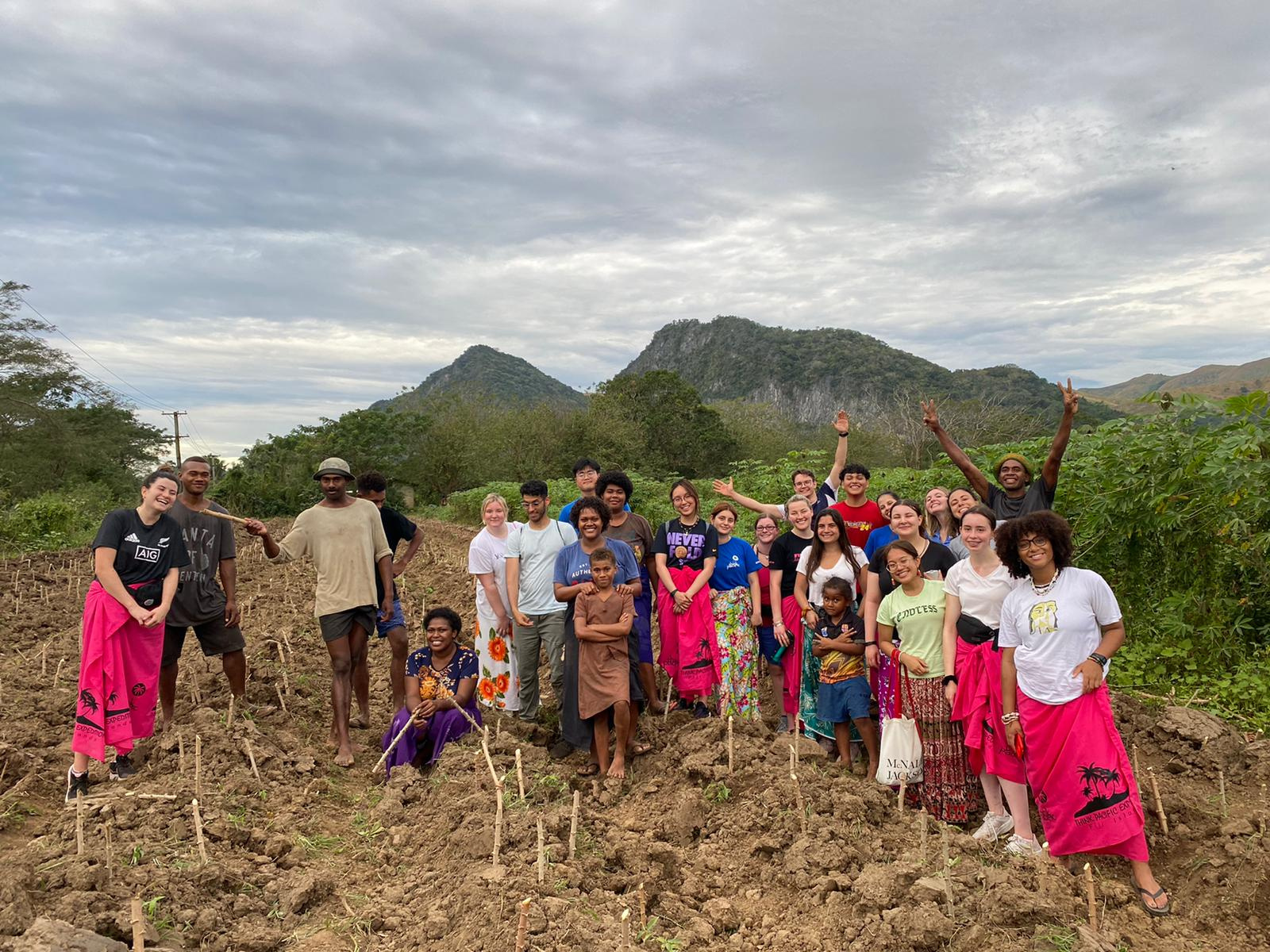 Myself and some of the volunteers stand with the youth and some children from the village on the farm. 