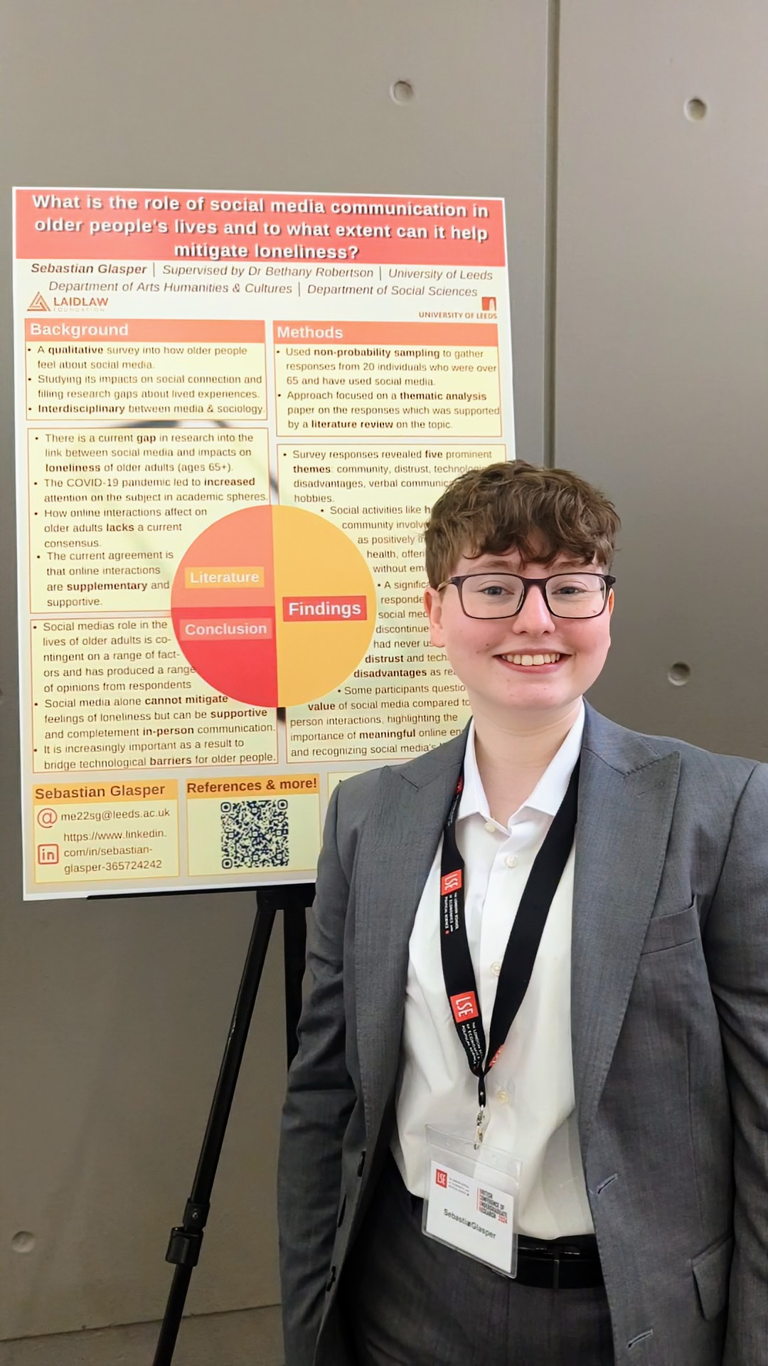 Myself, Sebastian, stood in front of my research poster with a grey backdrop.