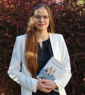 Photo of Zsuzsánna Réthi-Nagy facing the camera and holding a book.