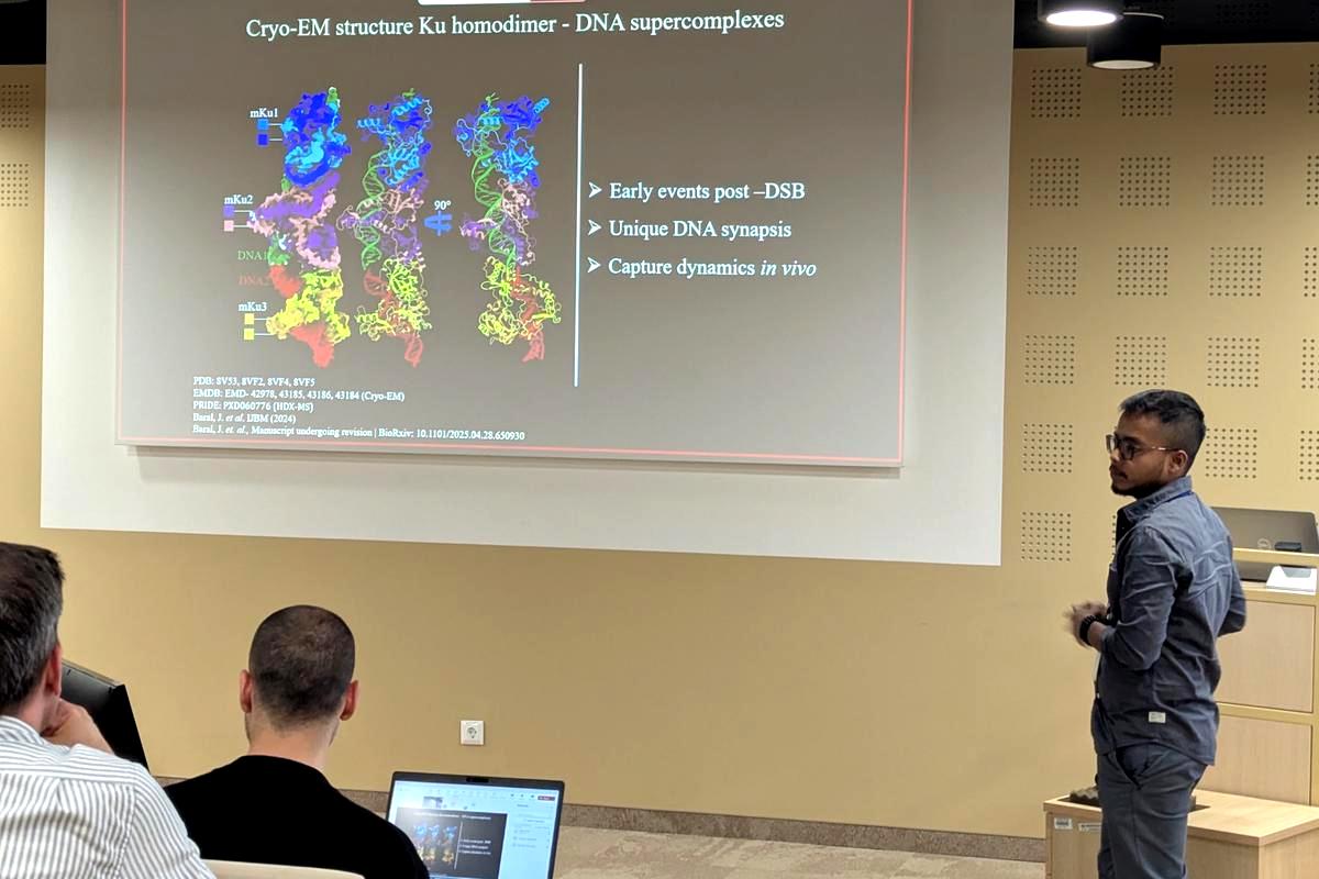 Joydeep Baral standing by his projected slides, showing his PhD research.