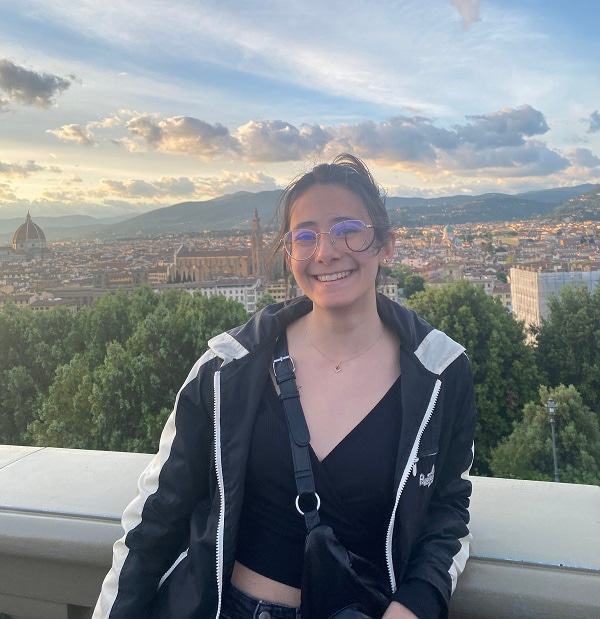 Photo of Sara León Álvarez smiling and facing the camera, with Florence, Italy showing on the background