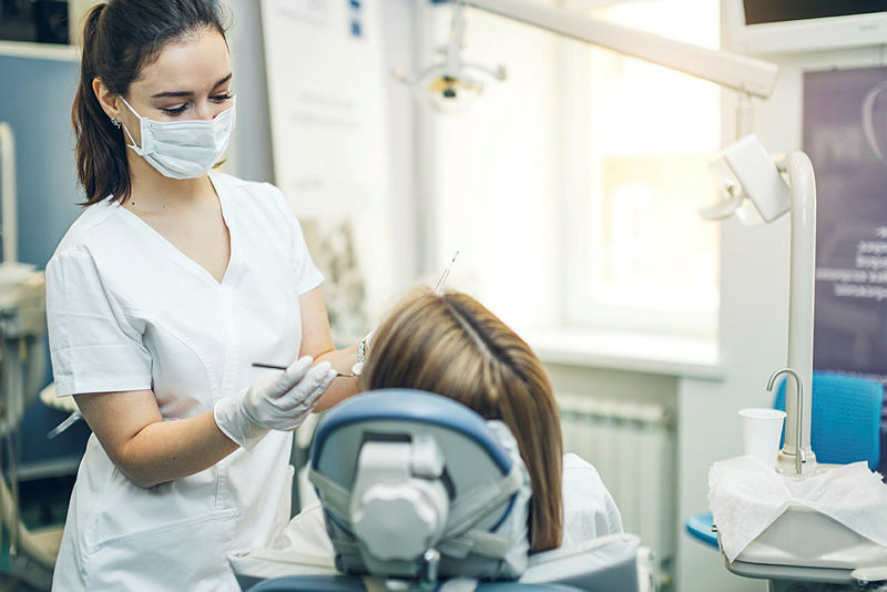 A dentist wearing a face mask treating a patient in a dental surgery