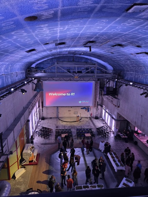 Photo taken from high up showing from the ceiling to the ground of a large room, with people standing below.