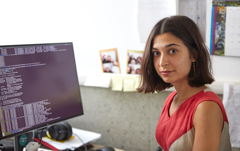 Photo of School Ambassador Sara Formichetti sitting at her computer and looking at the camera.
