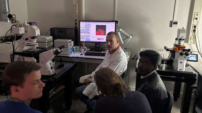 Koen van den Dries sitting by a computer and microscopy equipment.