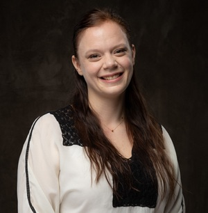 Portrait photo of Urša Čerček smiling at the camera, with a black background.