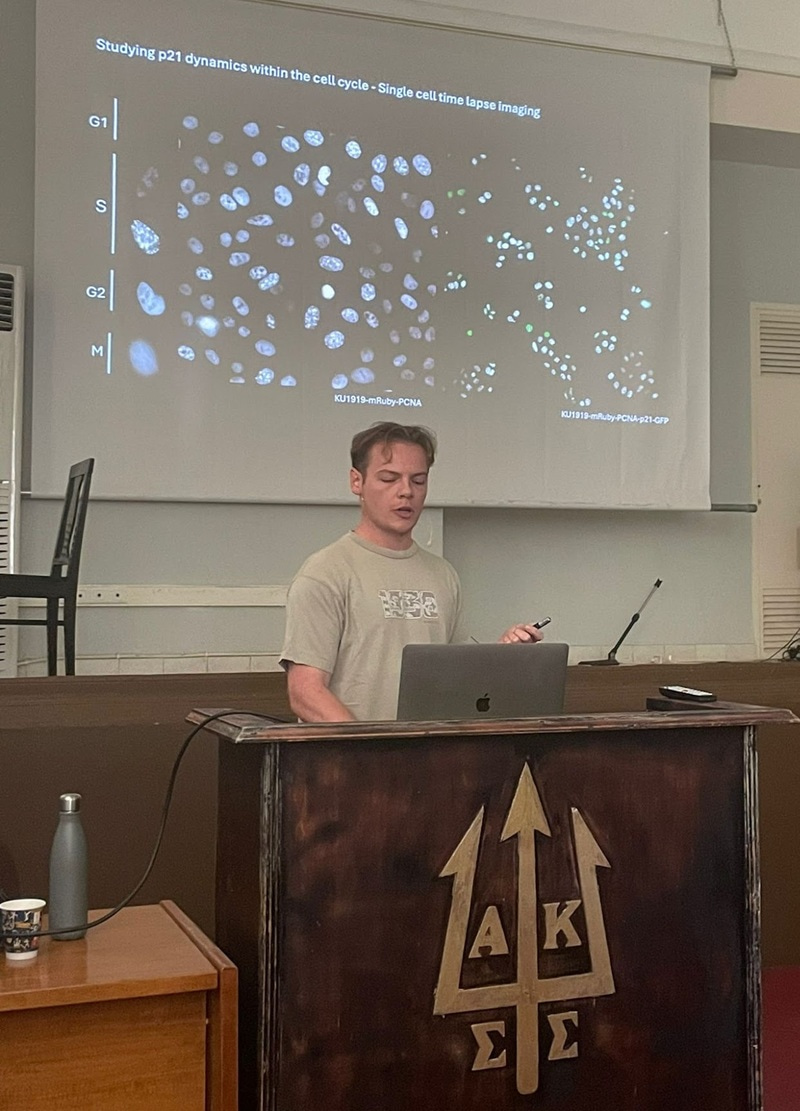 William Weston standing behind a lectern, presenting on a stage.