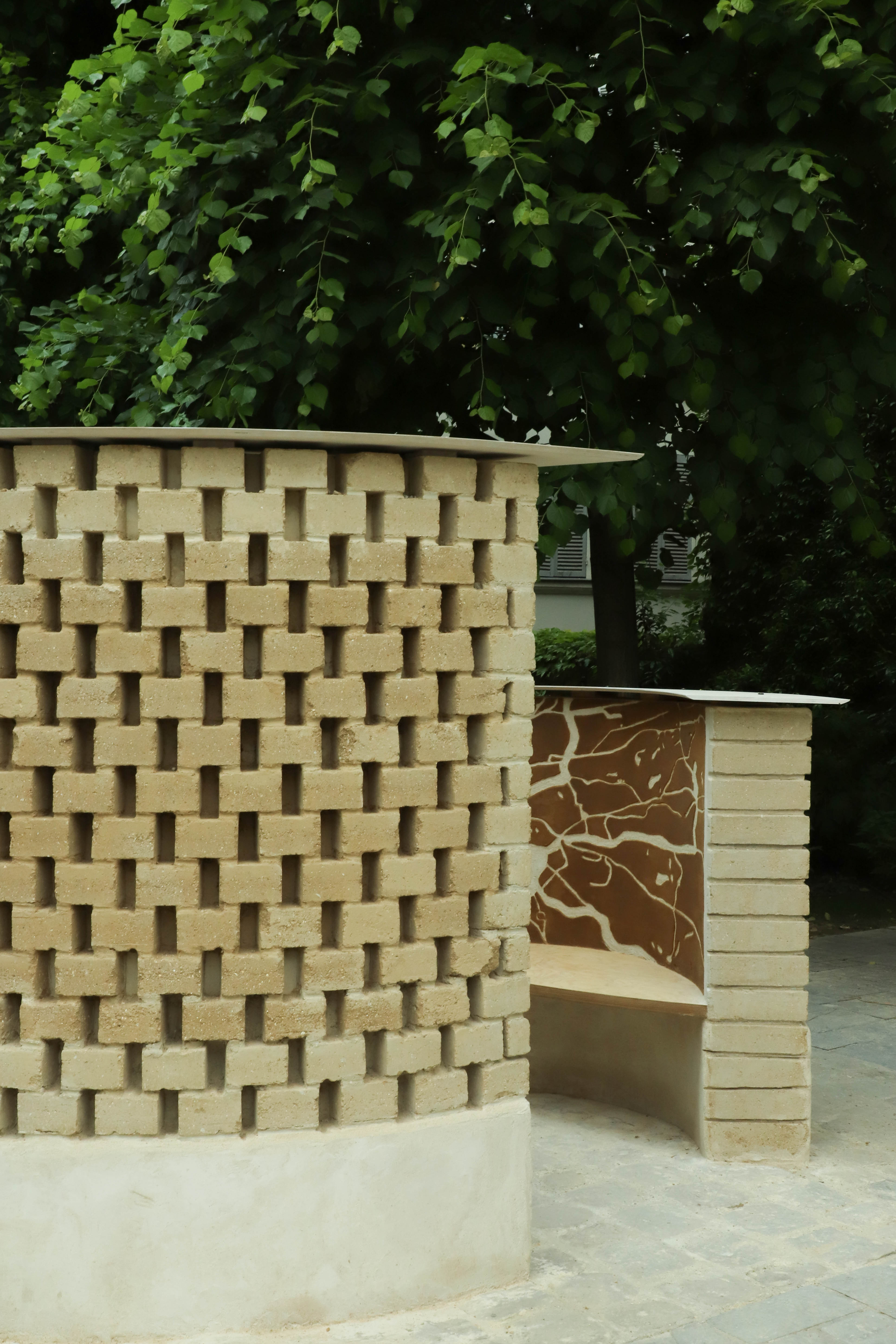 Two raw earth structures that are rounded with wood benches.