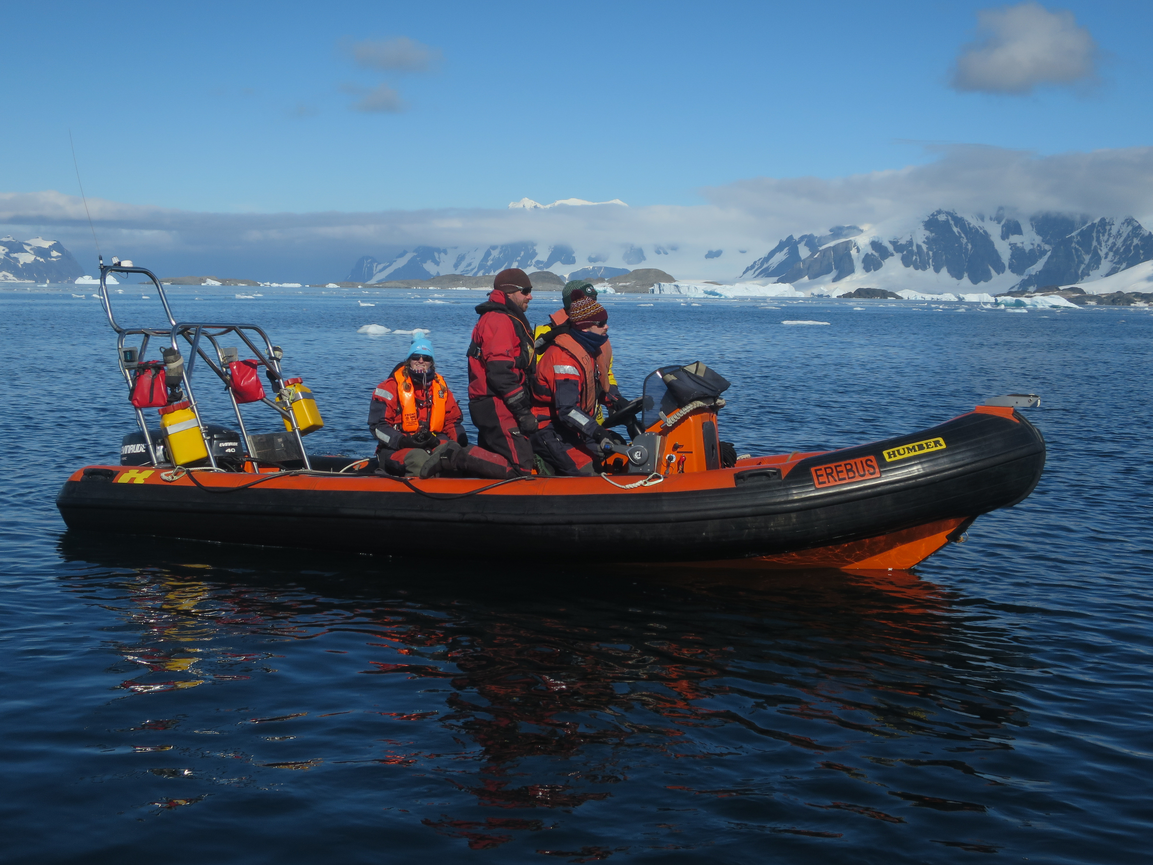 People in a small boat with icy mountains in the background