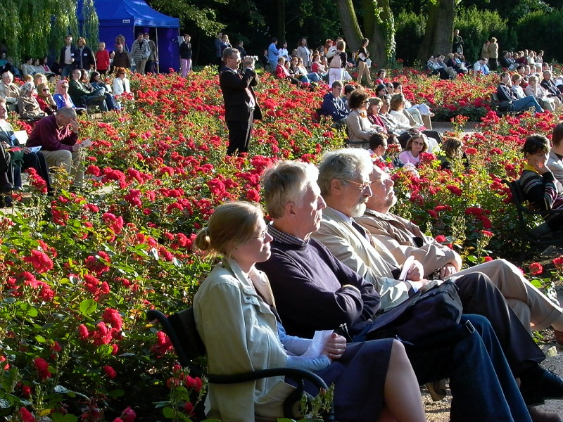 Photo of congress participants outdoors, sitting in a garden and watching one of the event activities.