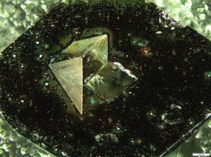 An optical microscope image of the prism used in the experiment. This 0.5 mm prism was attached to a 3 mm surface (darker background) with a square hole (center of image).