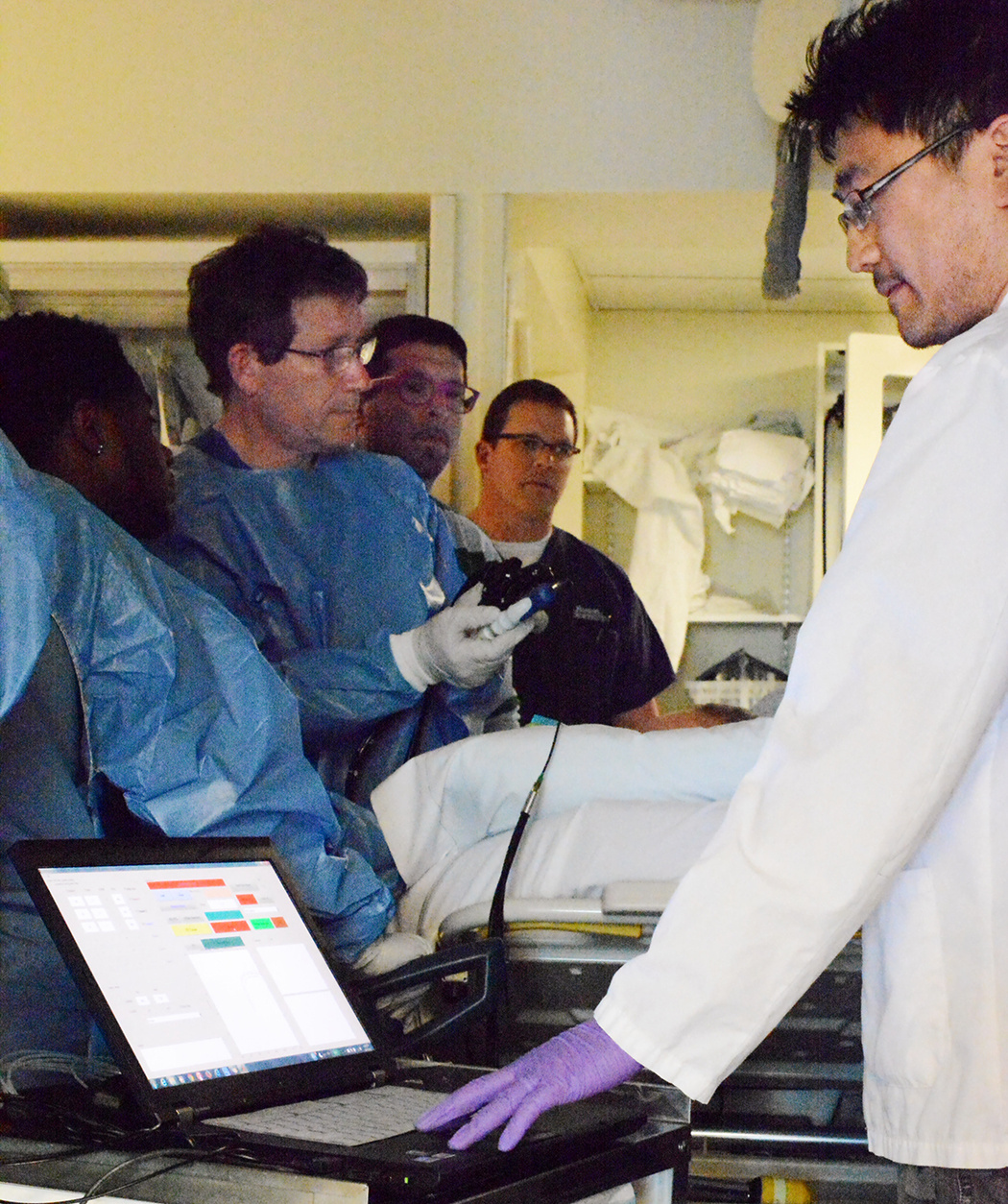 Figure 3. Collecting data with the new in vivo LSS clinical system for detection of early cancer in pancreatic cystic lesions during a routine endoscopic ultrasound-guided fine needle aspiration (EUS-FNA) procedure. Douglas K. Pleskow, MD (center) is controlling the position of the LSS fiber optic probe inside the pancreatic cyst using EUS guidance and Le Qiu, PhD (front right) is collecting the LSS cyst data.