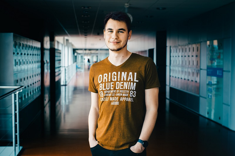 Portrait of Martin Toul facing the camera, with hands in pockets, and a corridor behind him. Photo by Irina Matusevic