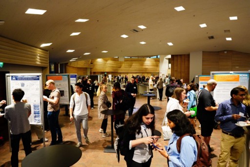Photo of attendees at a conference, talking and looking at the exhibition posters.