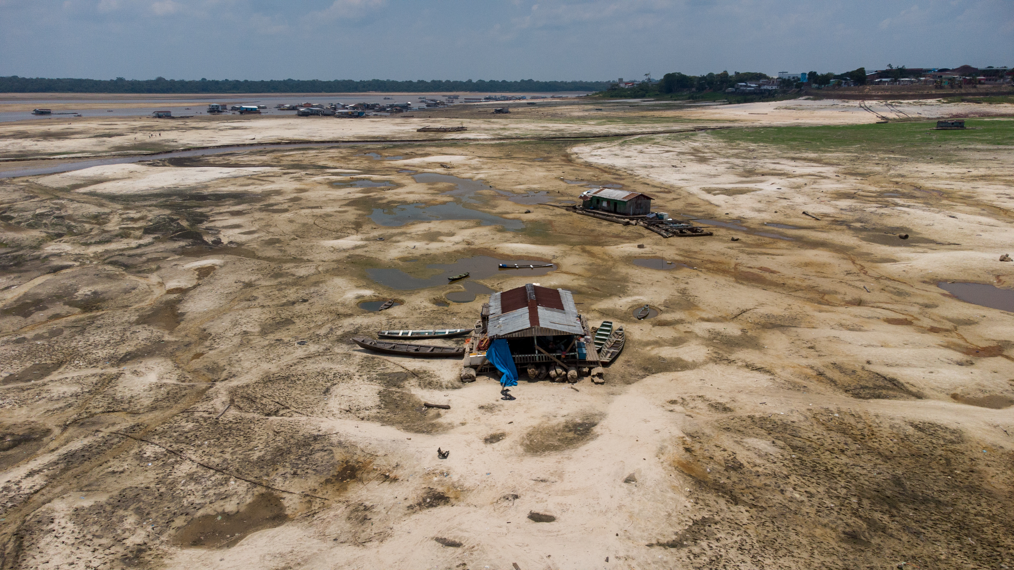 Traditional floating house trapped on a large sandbank that was exposed when river levels dropped during the extreme drought of 2023 in the town of Tefé, AM. Photo Credits: João Paulo Borges @drone_da_amazonia.