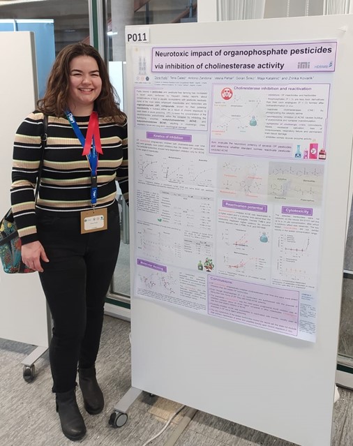 Dora Kolić standing in front of her research poster at the FEBS-IUBMB-ENABLE conference 2023 in Cologne..