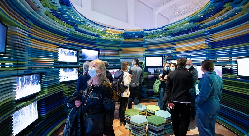 Photo showing attendees inside the video installation Triggered by Motion, which is a curved structure with screens embedded in it. The installation was displayed at the exhibition “Planet Digital”, which was a cooperation with the local Museum of Design. Photo credit to Frank Bruederli