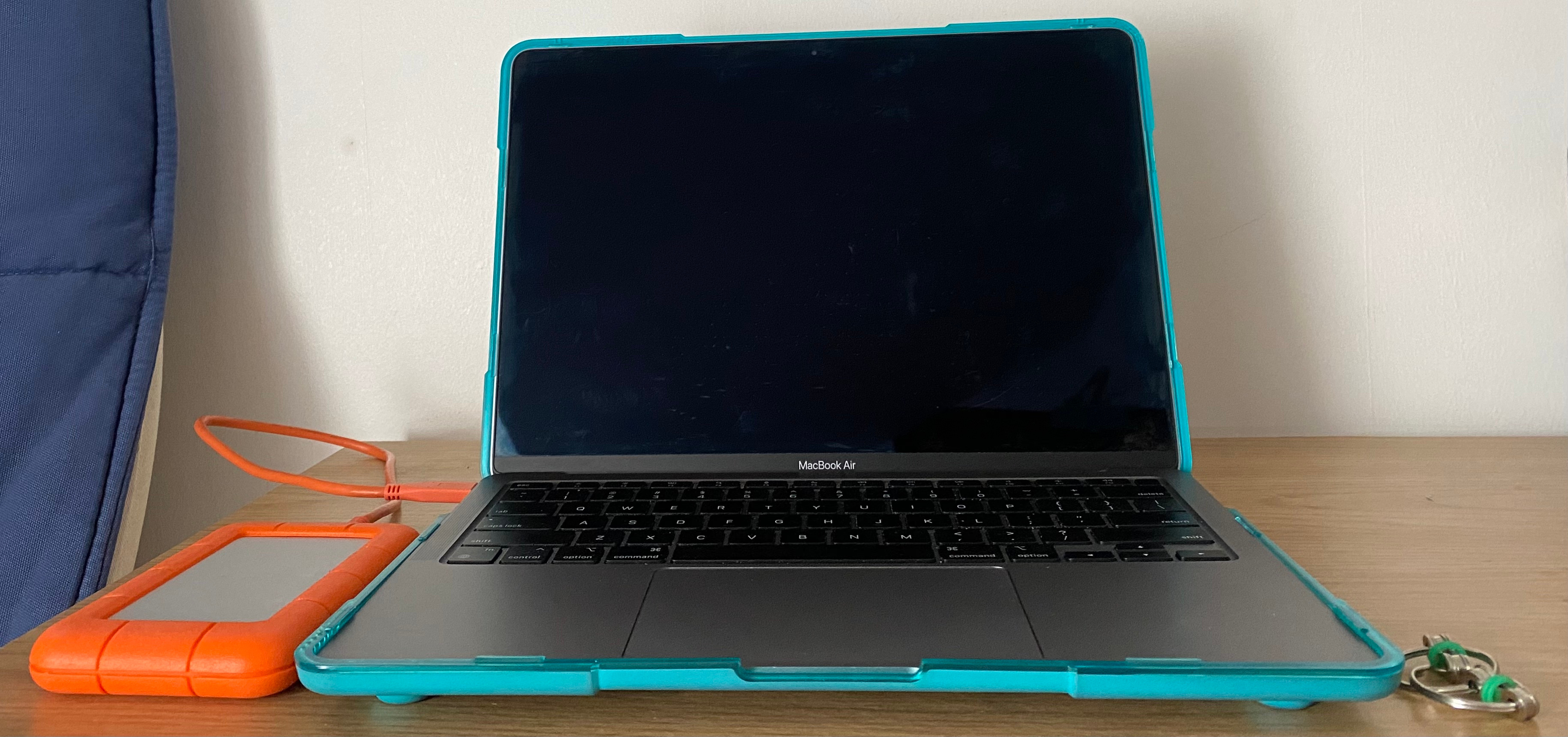 Pictured on the left is an orange external hard drive. In the middle is a laptop. Pictured on the right is a silver and green fidget toy.