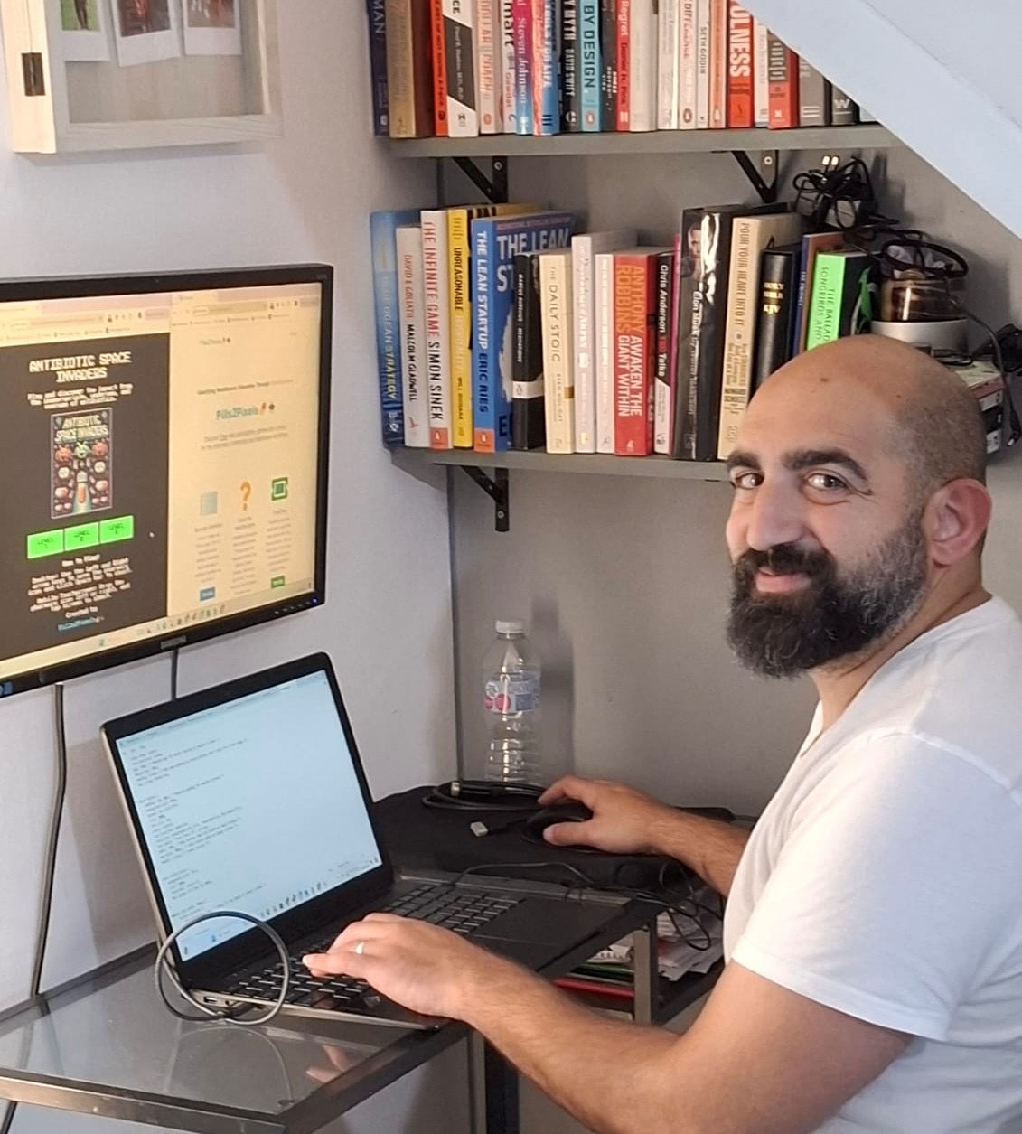 A man sits at a computer and smiles at the camera