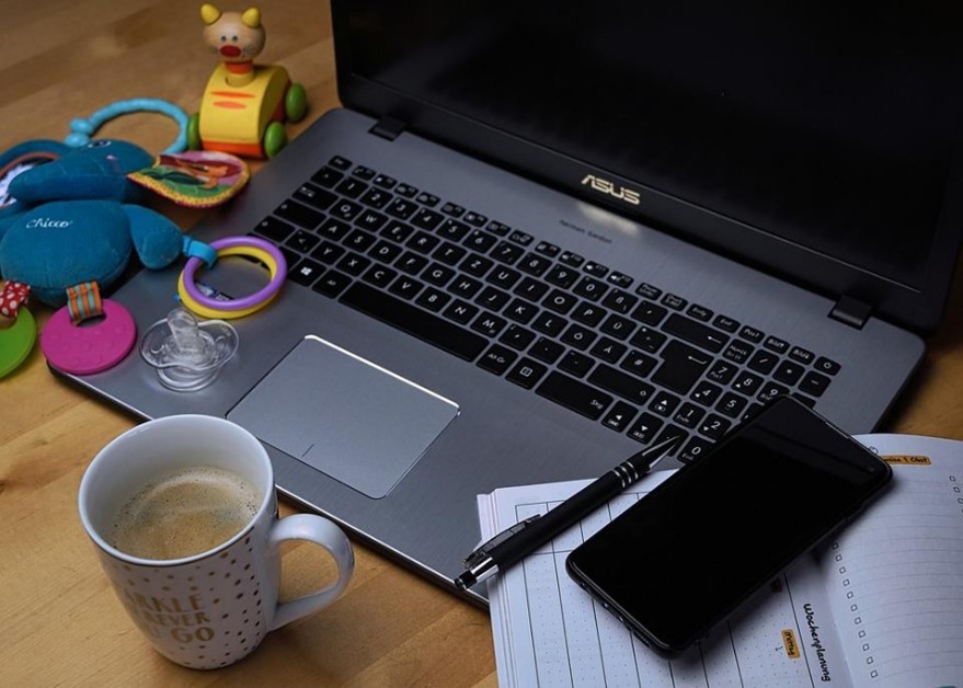 images of a laptop, phone and notebook on a table, next to it are baby toys