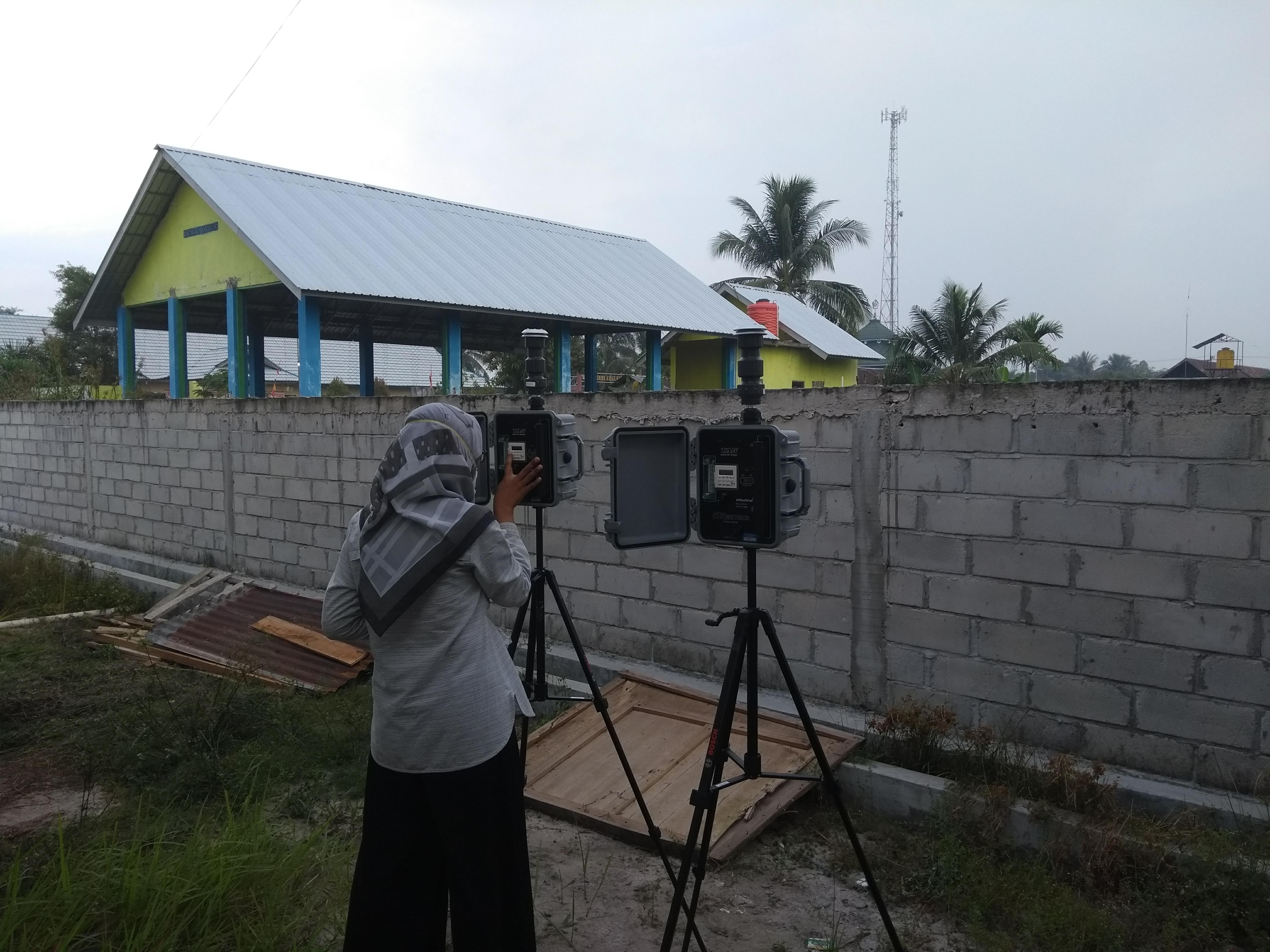 A researcher using a filter sampler on a tripod in an urban area