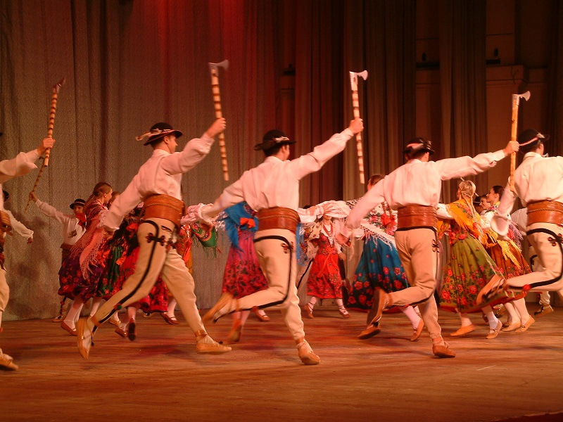 Photo of dancers dressed in traditional costumes and holding axes.