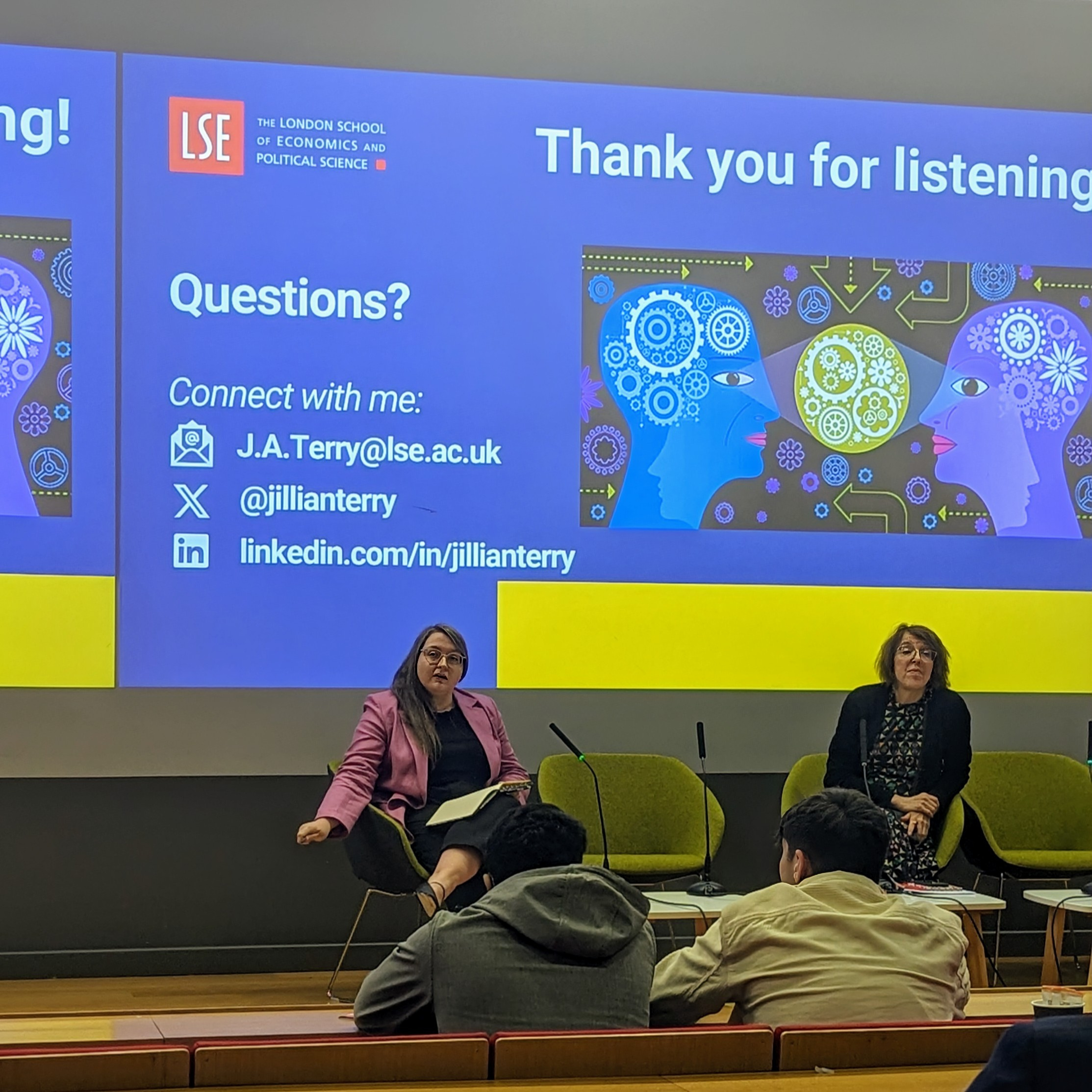 Pictured keynotes speaker Jillian Terry. She sits on stage with a notebook ready to answer questions from the audience.