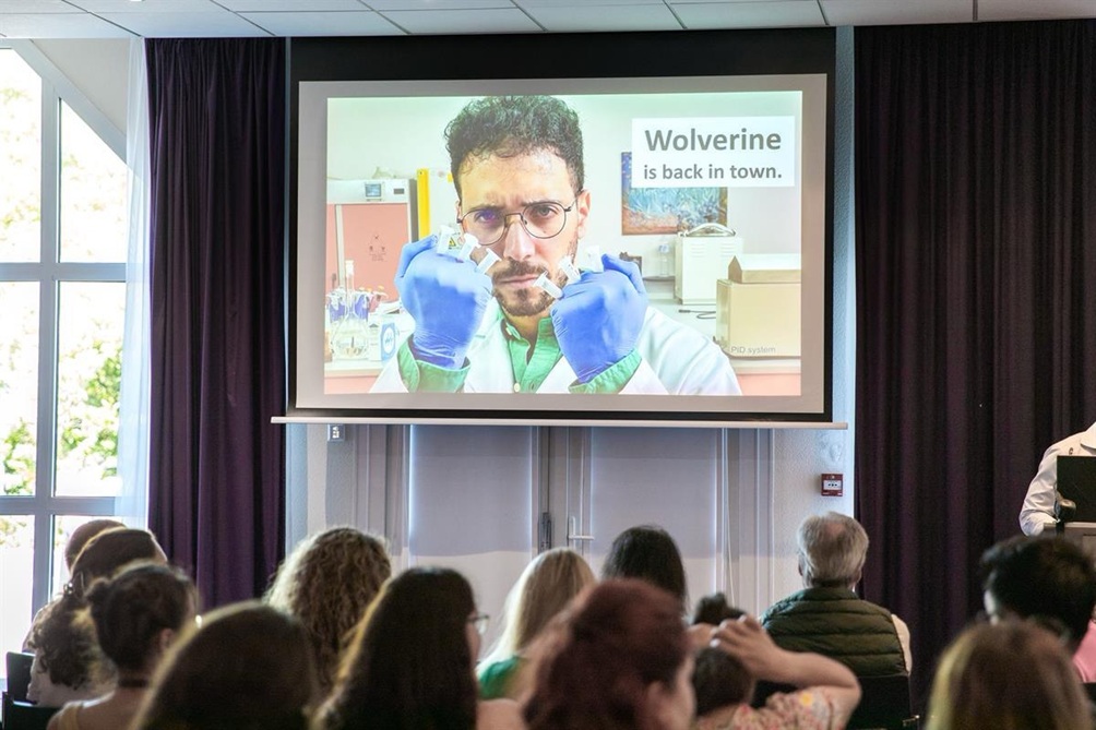 Photo of a slide of Ignazio Restivo's presentation, showing a photo of him holding Eppendorf tubes as claws with the caption "Wolverine is back in town".