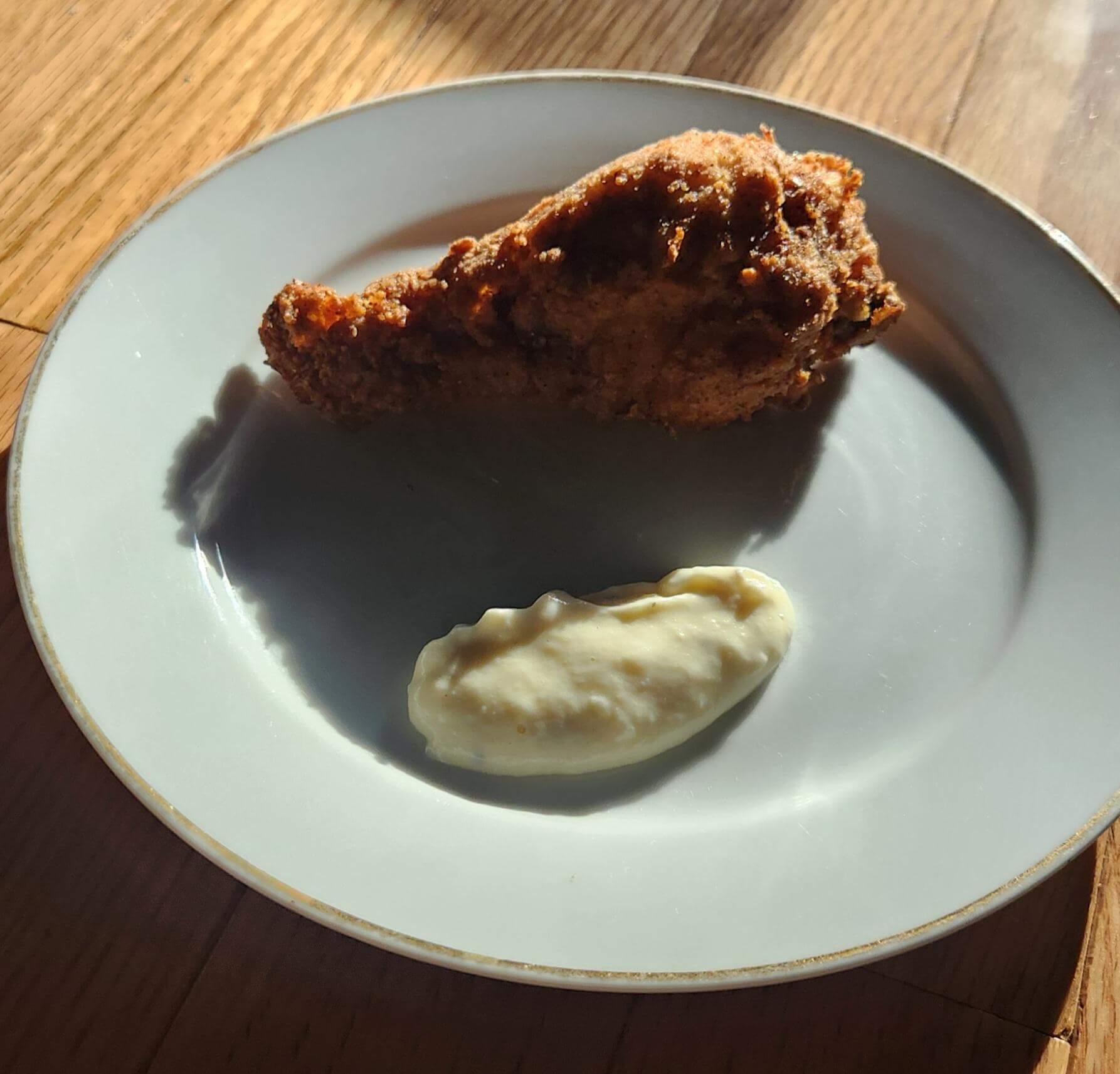 A piece of fried chicken on a plate with sauce