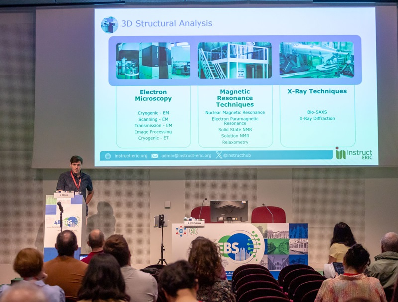 Photo of John Dolan from Instruct-ERIC, giving a talk in front of projected slides.