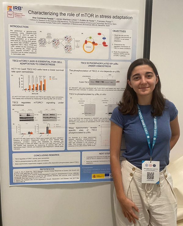 Photo of Ana Contreras standing by her research poster and looking at the camera.