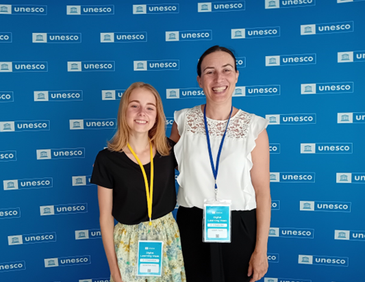 Two women standing in front of a blue backdrop