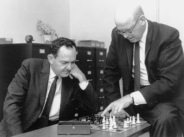 Herbert Simon and Allen Newell at a desk playing chess