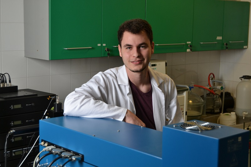 Portrait of Martin Toul facing the camera, surrounded by equipment in the Loschmidt Laboratories. Photo by Irena Halikova