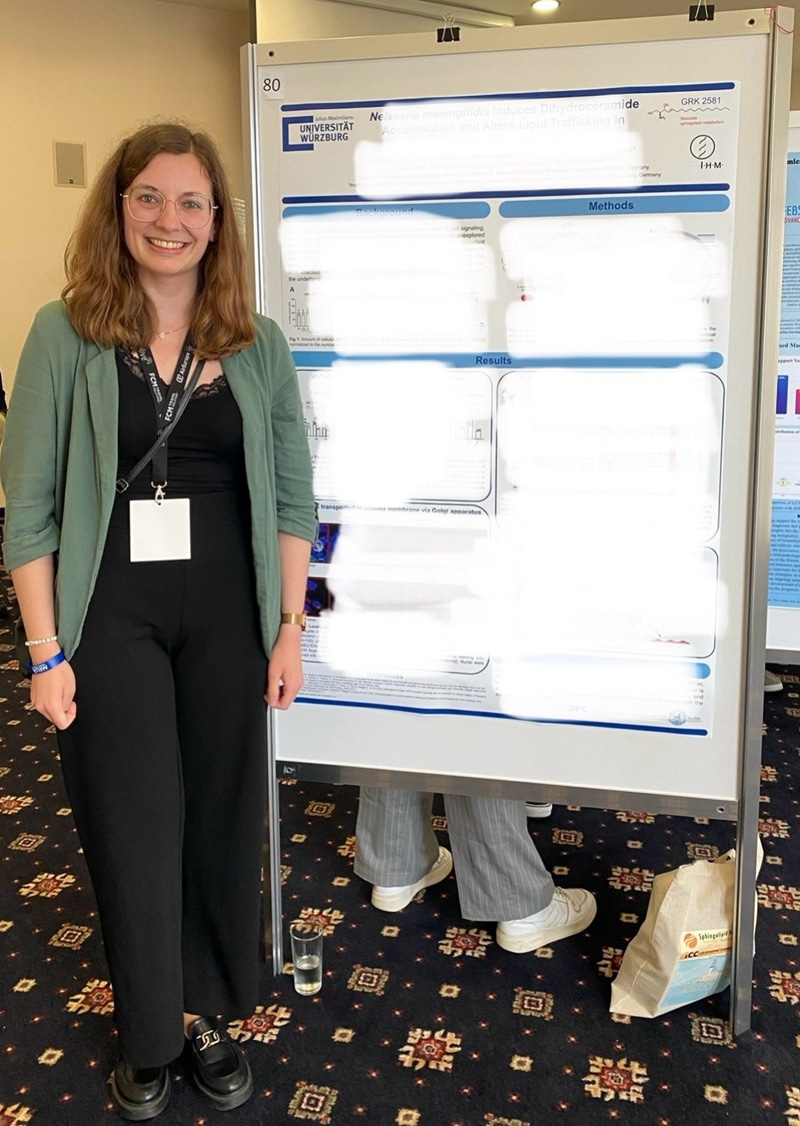 Alina standing by her research poster, smiling at the camera.